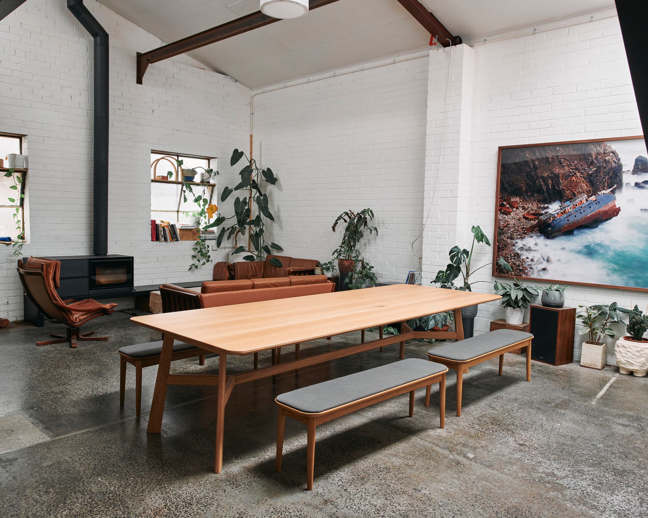Breakout dining — oak table and benches under a large framed seascape