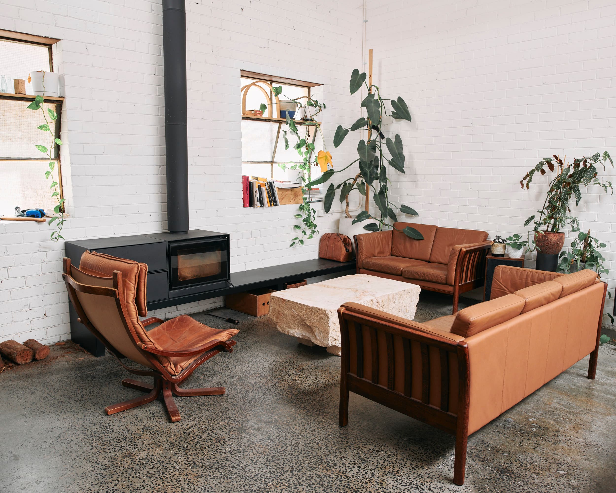 Client breakout at Crate Studio — tan leather lounges, wood heater and plants against white brick