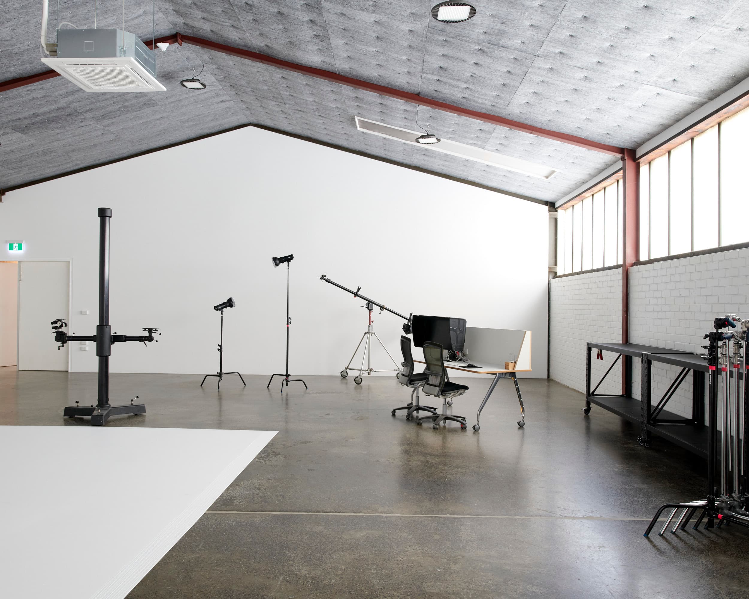 Wide view of Studio A — cyclorama edge, digi desk with monitor, clerestory windows and grip shelving